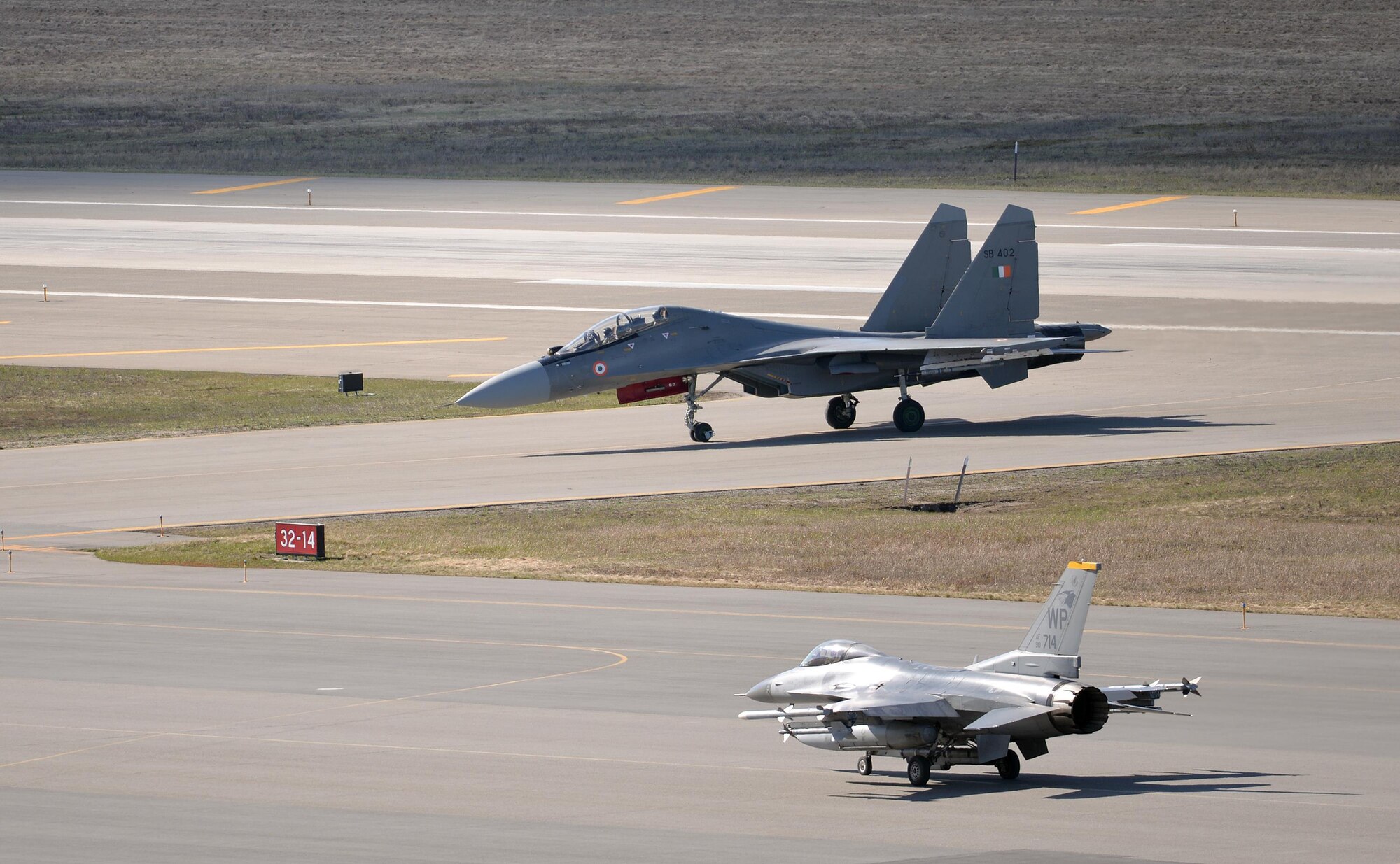 A U.S. Air Force F-16 Fighting Falcon assigned to the 80th Fighter Squadron out of Kunsan Air Base, Republic of Korea, waits on the Eielson Air Force Base, Alaska, flight line May 6, 2016, as an Indian air force Su-30 MKI aircraft taxis by after a RED FLAG-Alaska (RF-A) 16-1 mission. RF-A is a series of Pacific Air Forces commander-directed field training exercises for U.S. and partner nation forces, enabling joint and international units to sharpen their combat skills by flying simulated combat sorties in a realistic threat environment inside the Joint Pacific Alaska Range Complex, the largest instrumented air, ground and electronic combat training range in the world. (U.S. Air Force photo by Master Sgt. Karen J. Tomasik/Released)