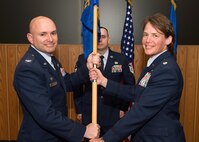 Col. David R. Dunklee, 66th Air Base Group commander, passes the 66th Medical Squadron guidon to Lt. Col. Lynn M. Shinabery during a change of command ceremony at the O'Neill Auditorium on base May 12, while Master Sgt. Jason Oliver, 66 MDS first sergeant, looks on. As commander of Hanscom's Medical Treatment Facility, Shinabery is responsible for the daily operations of 157 personnel and a 125,000 beneficiary population. (U.S. Air Force photo by Jerry Saslav)