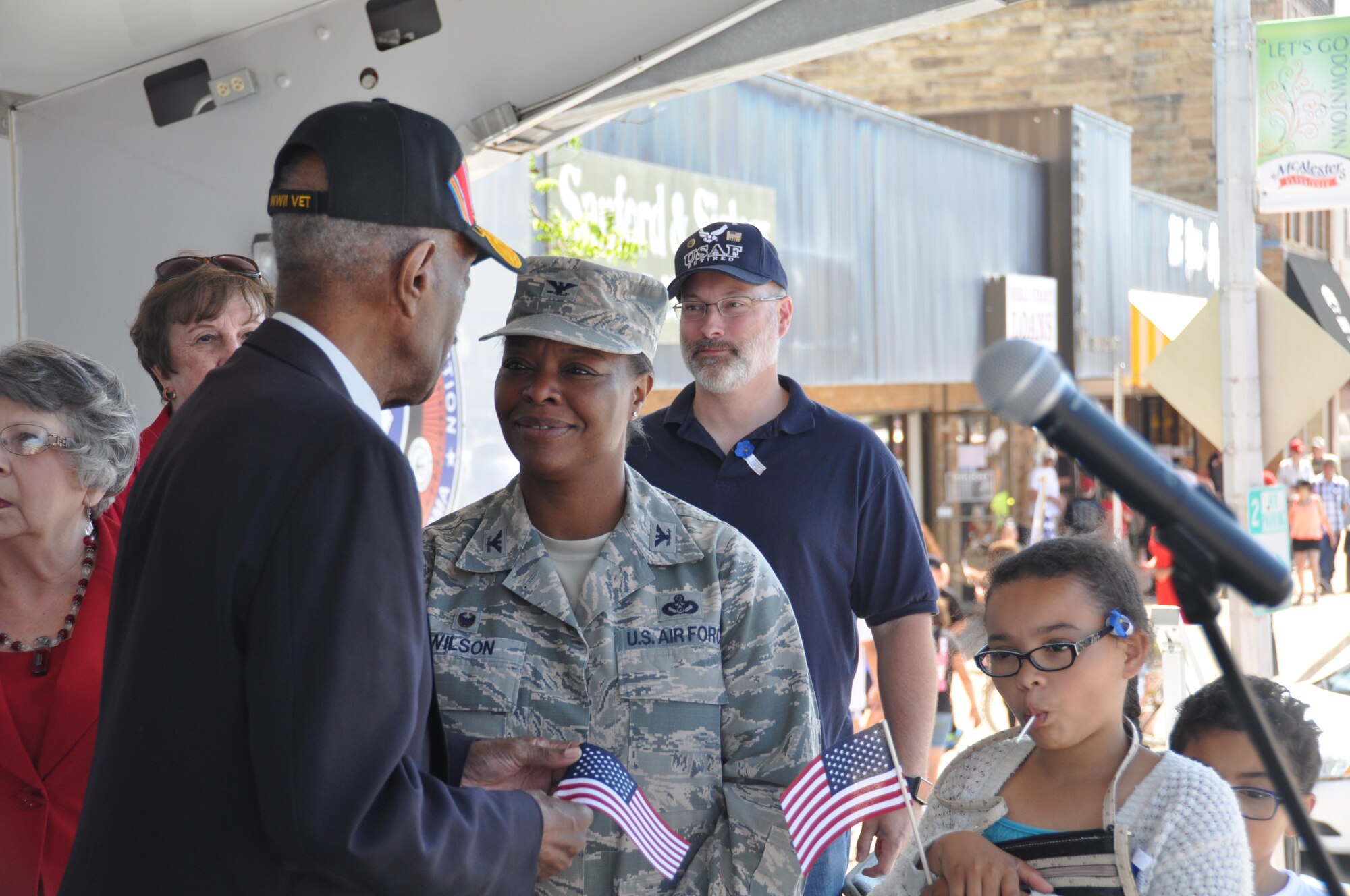 Colonel Stephanie Wilson, 72nd Air Base Wing commander, talks to Mr. James Ward, a 93-yr old Navy veteran of World War II on the reviewing stand at the McAlester Armed Forces Day parade held May 6 in McAlester, Okla. Looking on are Mrs. Barbara Kleager, wife of retired Army Colonel Jerald Kleager, chairman of the McAlester Armed Forces Day Committee and Col. Wilson’s husband Scott Wilson. Col. Wilson was the Grand Marshall of the parade. (Army photo by Paul Rogers/Released
