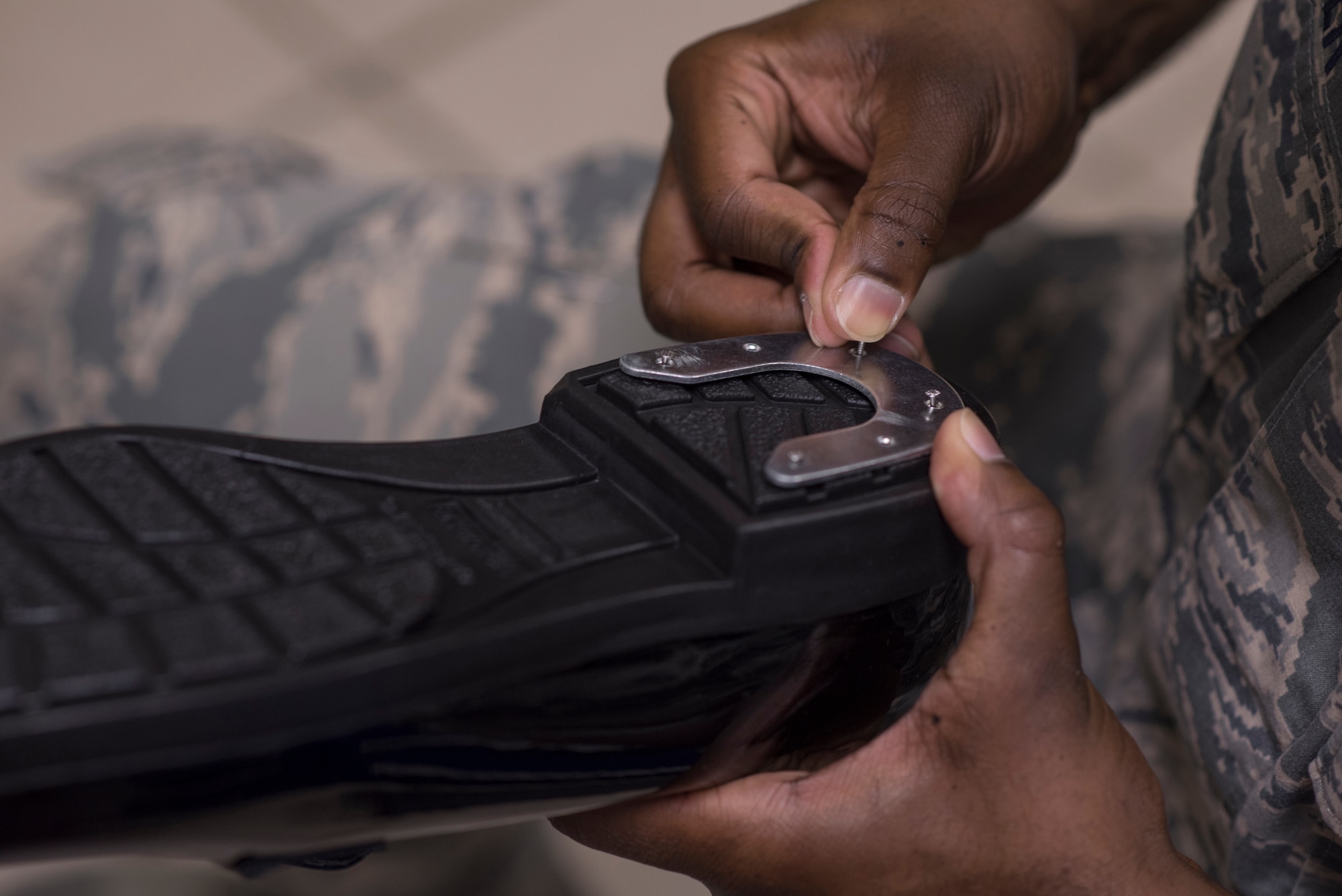 Senior Airman Daniel Wheeler, Yokota Honor Guard, pushes in nails to affix horseshoe heel clickers to a pair of low quarters during honor guard training at Yokota Air Base, Japan, May 11, 2016. The heel clickers are nailed into the bottom of the shoe making an audible clicking noise when the Airmen take their steps. (U.S. Air Force photo by Staff Sgt. Michael Washburn/Released)