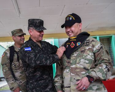 Honduran Army Brig. Gen. Rene Ponce Fonseca gifts a bandana and hat to U.S. Army Brig. Gen. James P. Wong after a Task Force-Caiman-sponsored Regionally Aligned Forces-Central America training course closing ceremony in Tamara, Honduras, April 30, 2016. Ponce is the Honduran Army Forces commander and Wong is the deputy commanding general, Army National Guard of U.S. Army South. (U.S. Air Force photo by Staff Sgt. Siuta B. Ika)