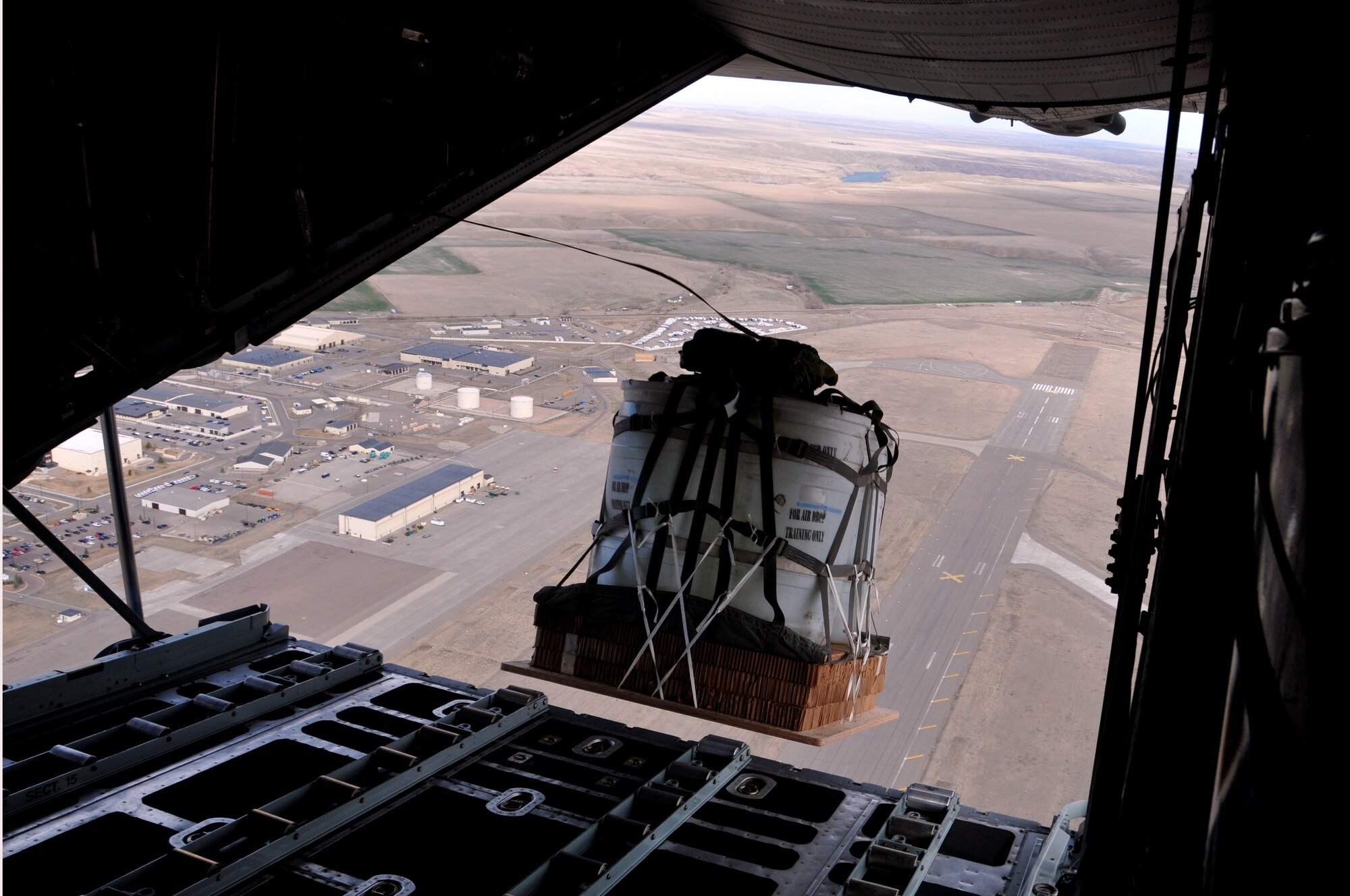 A training cargo load exits a Montana Air National Guard C-130 cargo aircraft over the drop zone Chargin' Charlie near Malmstrom Air Force Base, Mont. March 5, 2016. Each load weighs nearly 1,000 pounds and was dropped from an altitude of 1500 feet. (U.S. Air National Guard photo/Tech. Sgt. Michael Touchette)
