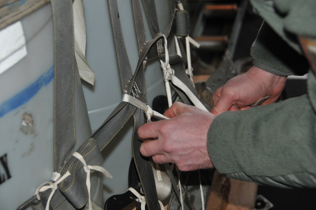 A loadmaster from the 186th Airlift Squadron secures a training cargo load aboard a Montana Air National Guard C-130 cargo aircraft. The cargo was intended to be dropped at the Chargin' Charlie Drop Zone at Malmstrom Air Force Base, Mont. March 5, 2016. Each load weighs nearly 1,000 pounds and was dropped from 1500 feet. (U.S. Air National Guard photo/Tech. Sgt. Michael Touchette)

