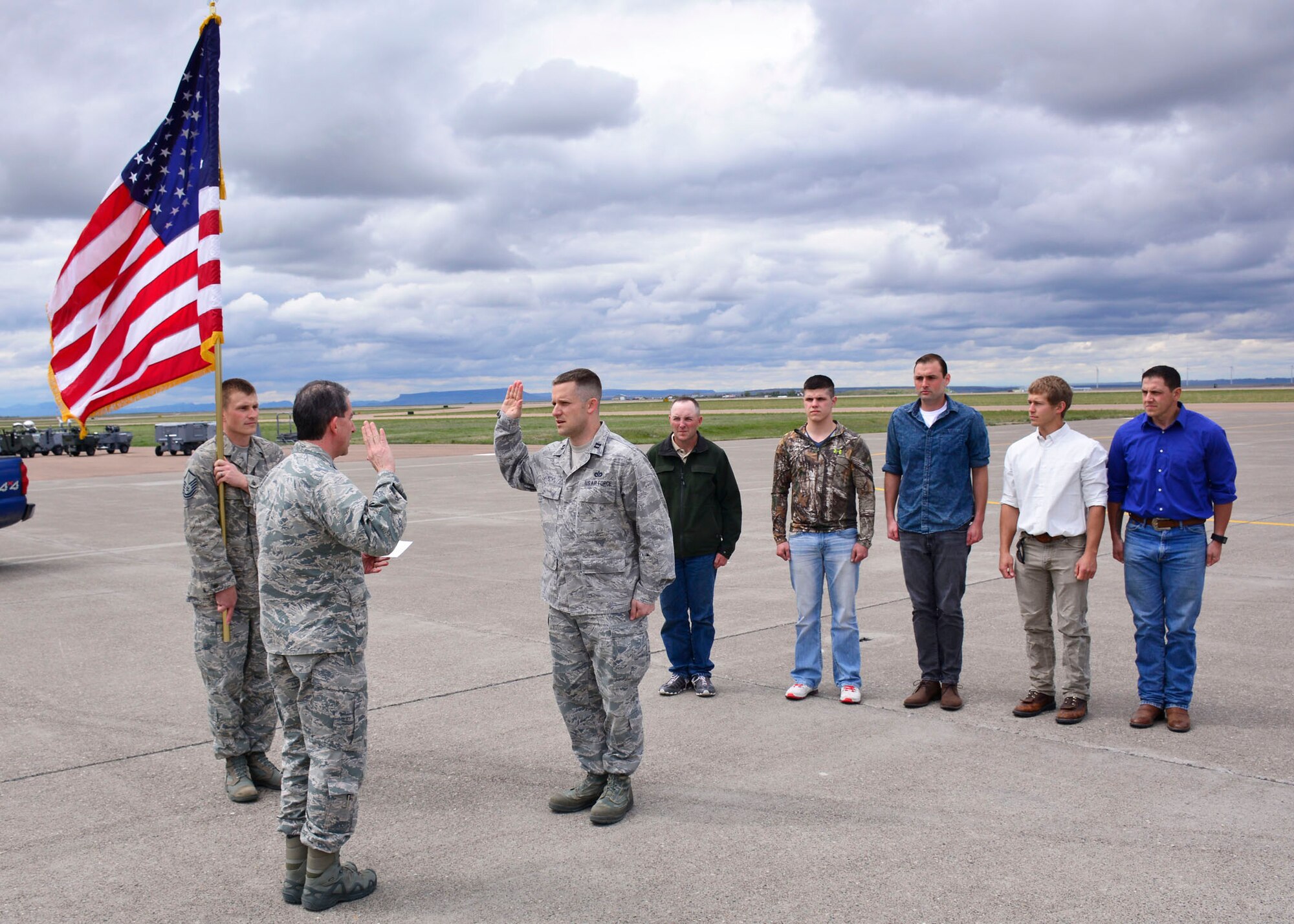 Col. Thomas Mora, 120th Airlift Wing vice commander, swears in Capt. Kevin Ochs, 219th RED HORSE engineer, on the 120th Airlift Wing flight line in front of a C-130 Hercules April 30, 2016. Ochs lead five new enlistees through the initial oath of enlistment after taking his oath. (U.S. Air National Guard photo/Senior Master Sgt. Eric Peterson)