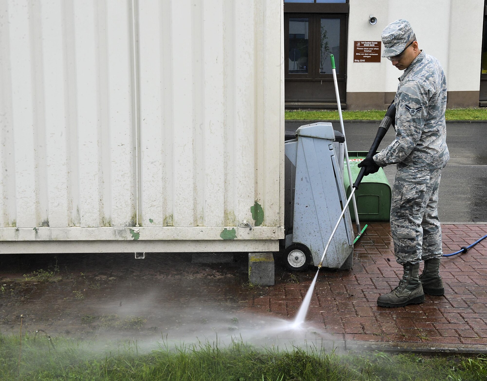 Airman 1st Class Jason Tittles, 1st Combat Communications electrical power production journeyman, power-washes a sidewalk during a base pride day May 10, 2016, at Ramstein Air Base, Germany. Airmen pulled weeds, swept, power-washed and raked leaves to ensure their work areas were clean. (U.S. Air Force photo/Senior Airman Larissa Greatwood)