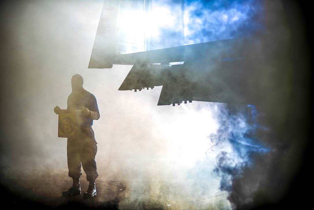 Navy Airman John Shaw holds a flag to signify a fire during a general quarters drill in the hangar bay of the USS Harry S. Truman in the Arabian Gulf, May 11, 2016. The Truman Carrier Strike Group is supporting Operation Inherent Resolve and other security efforts in the U.S. 5th Fleet area of responsibility. Navy photo by Petty Officer 3rd Class Mason M. Gillan