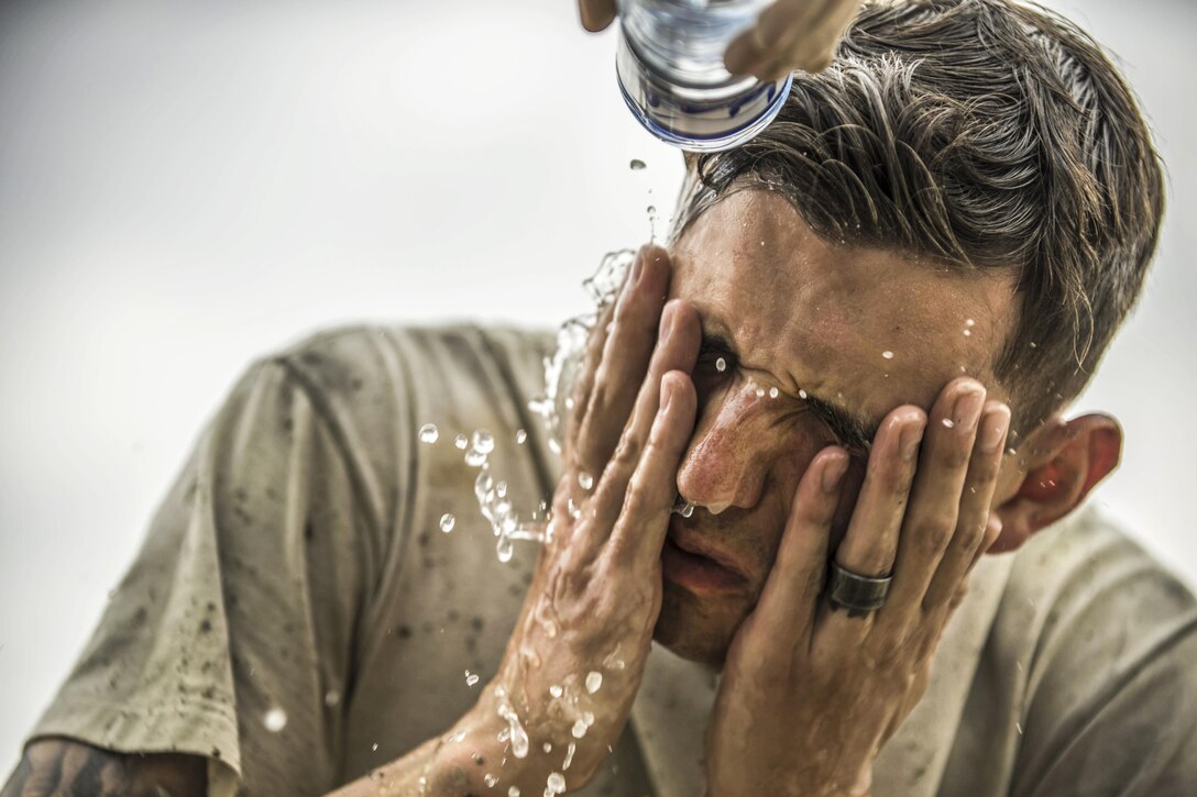 Air Force Senior Airman Jacob Nevills washes the concrete from his face after helping fill a footer at Bagram Airfield, Afghanistan, May 3, 2016. Nevills is assigned to the 455th Expeditionary Civil Engineer Squadron, whose members dug eight trenches to house eight footers for placing four relocatable buildings. Air Force photo by Senior Airman Justyn M. Freeman