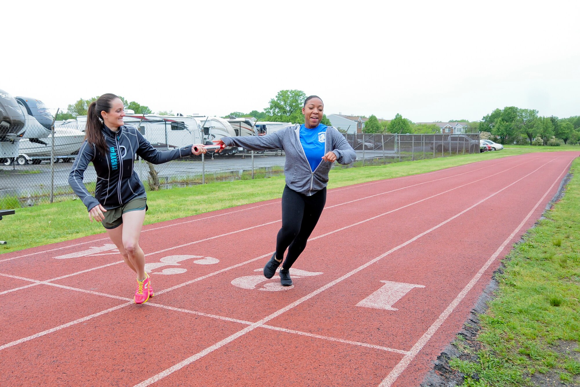 Airman 1st Class Kaylah Smith, 459th Operation Support Squadron aviation resource manager (right), passes a relay baton to Capt. Katie Pittinger, 459th Aeromedical Evacuation Squadron flight nurse (left), during a Holocaust Remembrance Month run at the Virginia Track on Joint Base Andrews May 9. More than a dozen volunteers came out from the 459th to help support the 24-hour vigil run, which started May 9 at 8:30 a.m. and ended May 10th at 8:30 a.m. (U.S. Air Force photo by Staff Sgt. Kat Justen)