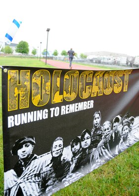 A 459th Airman runs past a banner recognizing victims of the Holocaust during a Holocaust Remembrance Month run at the Virginia Track on Joint Base Andrews May 9. More than a dozen volunteers from the 459th came out to support the 24-hour vigil run, which started May 9 at 8:30 a.m. and ended May 10th at 8:30 a.m. (U.S. Air Force photo by Staff Sgt. Kat Justen)