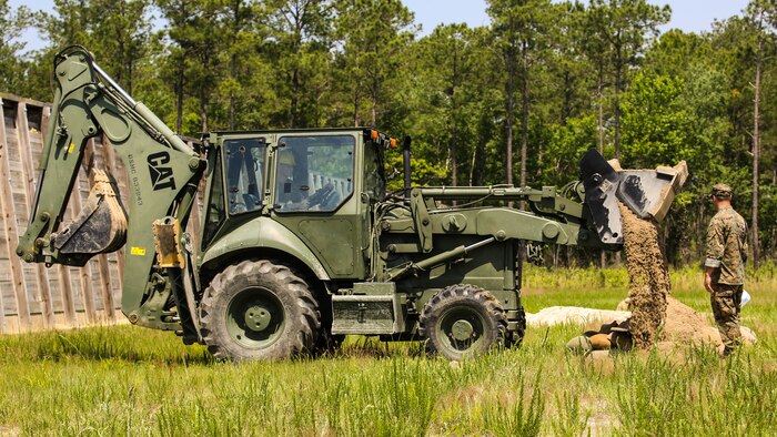 A Marine with 2nd Explosive Ordnance Disposal Company observes as a TRAM covers an explosive site with dirt during a Protective Works Demolition Range at Marine Corps Base Camp Lejeune, North Carolina, May 12, 2016. The EOD technicians were tasked to practice methods of protective works that allow them to reduce the fragmentation of explosives to preserve their surroundings. 