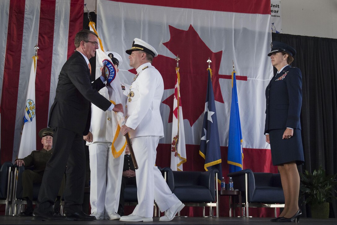 Navy Adm. Bill Gortney hands Defense Secretary Ash Carter a U.S. Northern Command flag during the change-of-command ceremony for the North American Aerospace Defense Command and Northcom at Peterson Air Force Base, Colo., May 13, 2016. Gortney relinquished command of NORAD and Northcom to Air Force Gen. Lori J. Robinson during the event. DoD photo by Air Force Senior Master Sgt. Adrian Cadiz