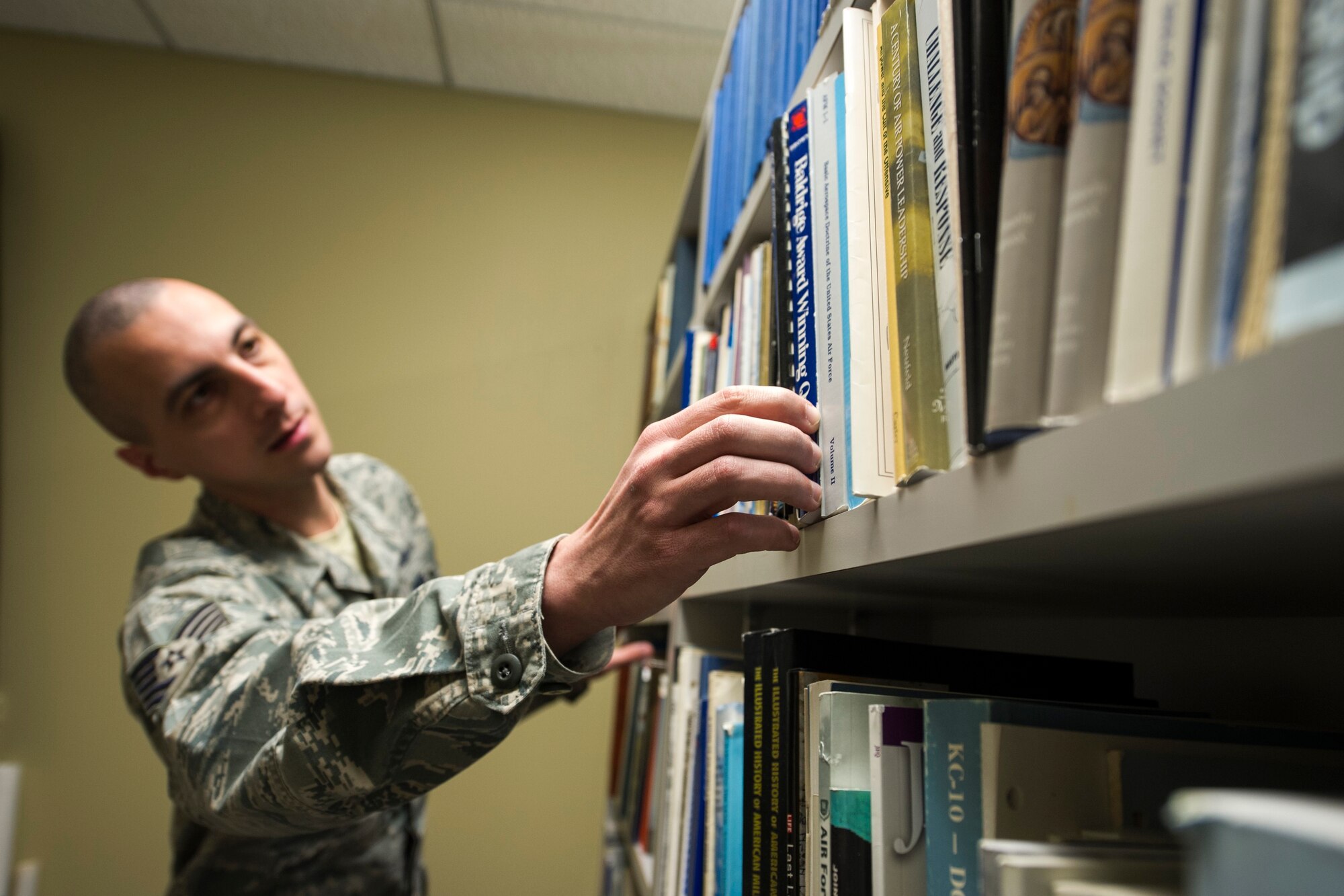 Tech. Sgt. Andrew Carr, 434th Air Refueling Wing historian, reaches for Basic Aerospace Doctrine of the Air Force, volume II, at Grissom Air Reserve Base, Indiana, April 9, 2016.  Air Force historians are responsible for creating yearly periodic analytical documents for the Air Force Reserve Command Historian at Robbins Air Force Base, Georgia. (U.S. Air Force photo/Staff Sgt. Katrina Heikkinen)