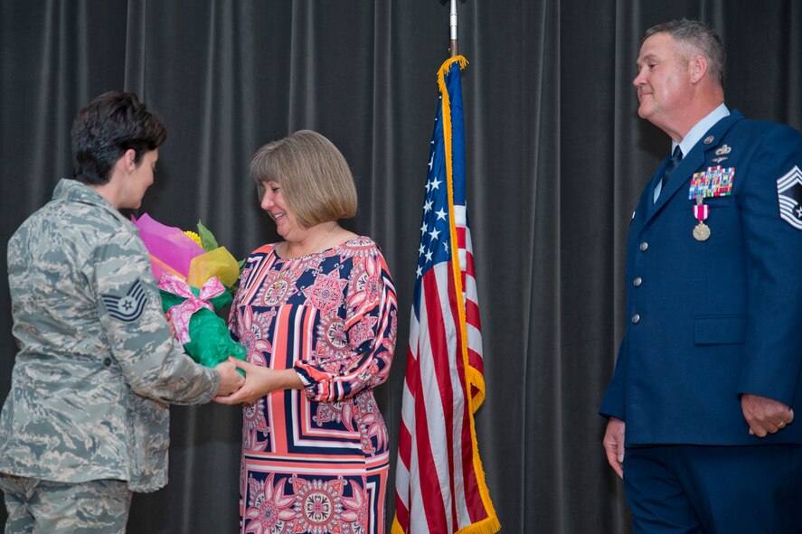 U.S. Air Force Reserve Tech. Sgt. Jacqueline Langston, unit training manager, 96th Aerial Port Squadron, presents Kelly Johnson, wife of Retired Chief Master Sgt. Todd Johnson, with a bouquet of flowers, during his retirement ceremony at Little Rock Air Force Base, Ark., May 14, 2016. Chief Johnson retired after 28 years of faithful service to his country in a room filled with family, friends and co-workers. (U.S. Air Force photo by Master Sgt. Jeff Walston/Released)     