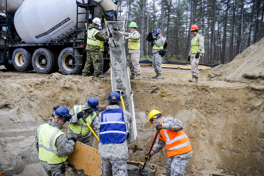 Airmen and Marine reservists pour concrete for the foundation for a porch on a new dining facility at Camp Hinds in Raymond, Maine, May 2, 2016. Air National Guard photo by Airman Tiffany Clark