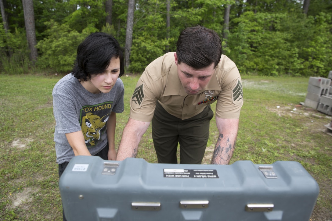 Sgt. Doug Hardy, an Explosive Ordnance Disposal technician with EOD Company, 8th Engineer Support Battalion, shows a student how to operate a robot during a robotics demonstration at Swansboro High School in Swansboro, N.C., May 10, 2016. Marines with EOD Co. demonstrated the capabilities of two robotics platforms to Swansboro High School's robotics club to help the students imagine the endless creative possibilities of robotics and engineering.