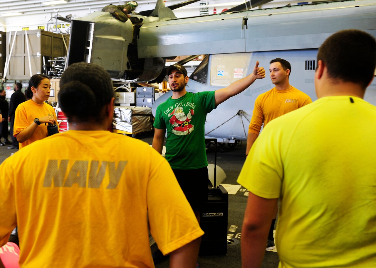 Rosalio Nieto, center, a civilian fitness specialist for Navy Morale, Welfare and Recreation, leads a fitness enhancement program class in the hangar bay aboard the amphibious assault ship USS Boxer, March 1, 2016. Navy photo by Petty Officer 2nd Class Jose Jaen