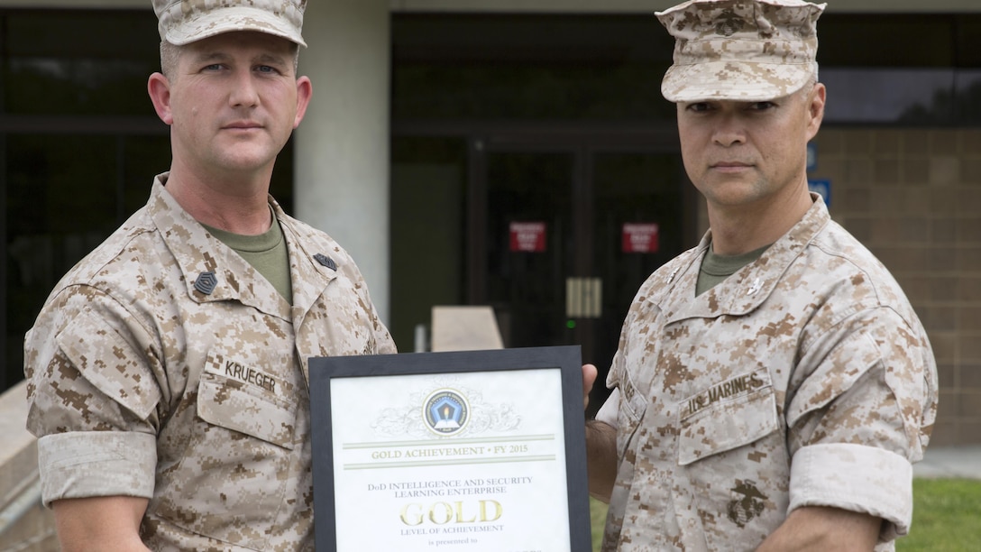 Col. John E. Walker Jr., right, commanding officer of Marine Corps Intelligence Schools, and Master Sgt. Eldar Krueger, MCIS S-6 chief, display the Department of Defense Intelligence and Security Learning Enterprise Gold Level of Achievement Award for 2015. MCIS received the Gold Level award for being the top school, chosen from a field of 52 formal learning centers encompassing $2 billion in resources and assets across the Department of Defense.