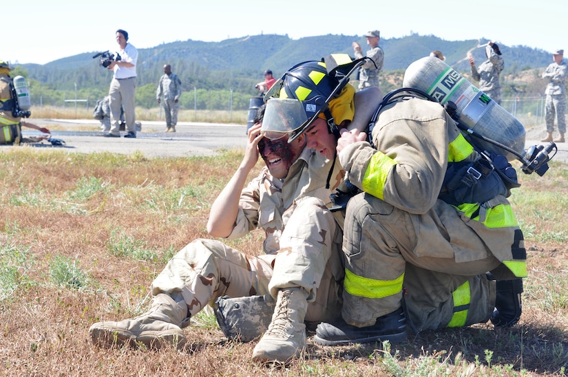 JOLON, Calif. – A Fire fighting Soldier with the 614th Engineer Detachment assists a simulated blinded casualty during a multi-unit mass casualty exercise at Fort Hunter Liggett’s Tusi Airfield, May 9. The exercise was apart of the Fort’s 16th Annual Warrior Exercise and the scenario encompassed a simulated helicopter crash, which had burst into flames and 32 casualties laid scattered around the helicopter. (U.S. Army photo by Sgt. Kimberly Browne, 350th Public Affairs Detachment)