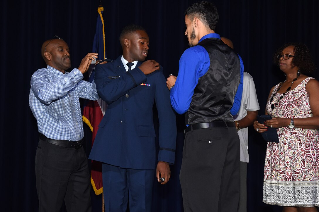 Friends and family pin gold bars on U.S. Air Force 2nd Lt. Hakeem Regis’ service coat during the Air Force ROTC Detachment 847 commissioning ceremony at Angelo State University's C. J. Davidson Conference Center, May 13, 2016. Detachment 847 commissioned four cadets into the Air Force during the ceremony. (U.S. Air Force photo by Staff Sgt. Laura R. McFarlane/Released)