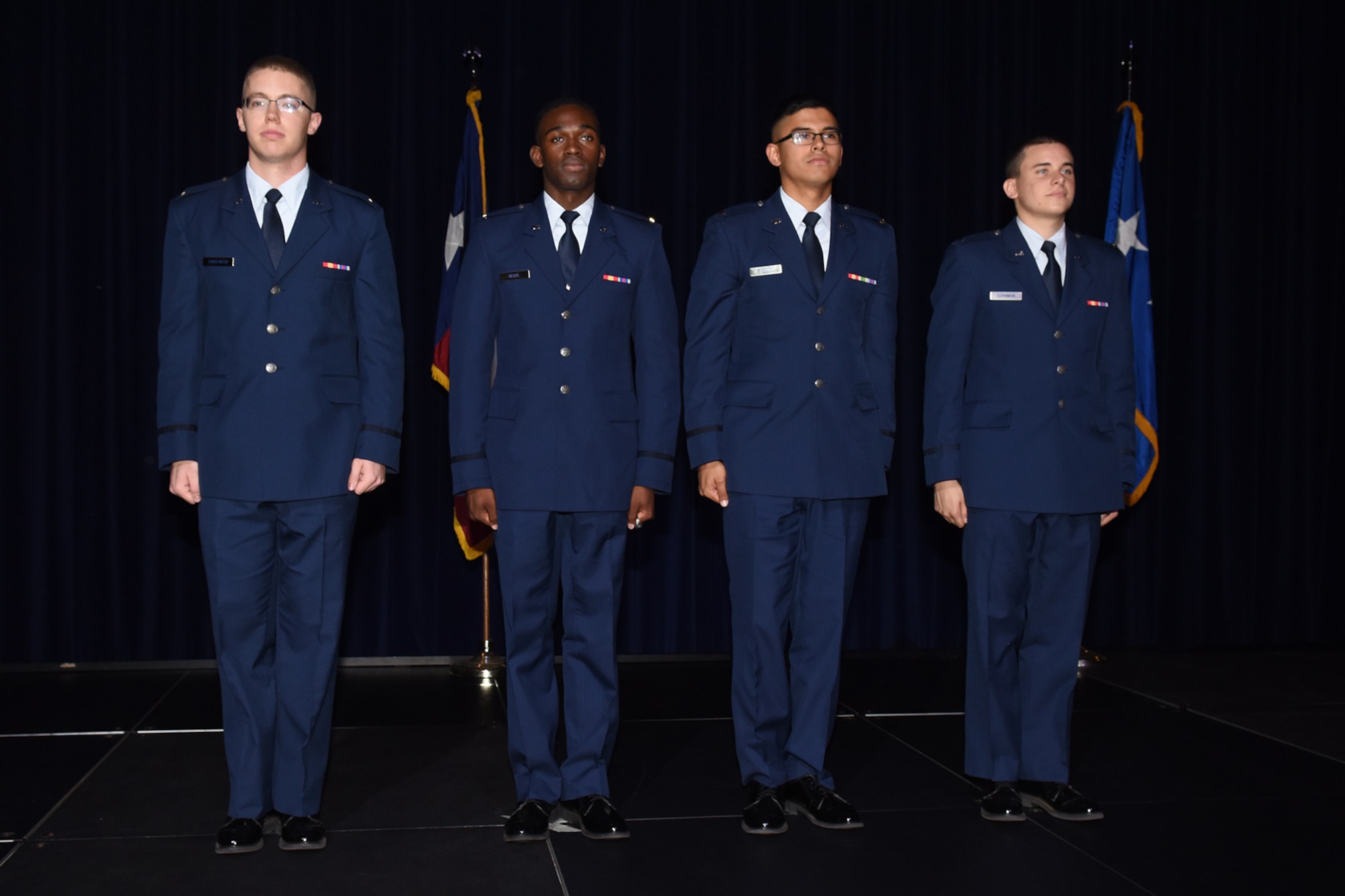 U.S. Air Force 2nd Lts. Quinn Sokolnicki, Hakeem Regis, Ruben Perez, and Matthew Cornman, prepare to lead the audience in the singing of the Air Force song following the Air Force ROTC Detachment 847 commissioning ceremony at Angelo State University's C. J. Davidson Conference Center, May 13, 2016. The ceremony included former or current military officers swearing in the cadets, friends and family members pinning the rank to their uniform, and former or current enlisted members rendering the new officers their first salute. (U.S. Air Force photo by Staff Sgt. Laura R. McFarlane/Released)
