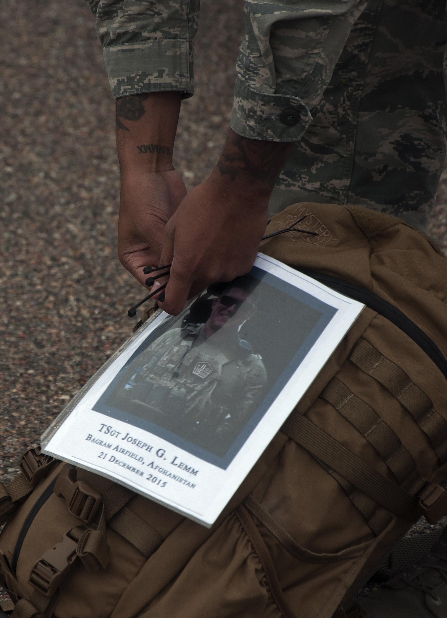 A 90th Security Forces Group defender attaches a memorial photo of Tech. Sgt. G. Lemm, a defender who lost his life in action, on to a backpack May 6, 2016, before participating in a memorial 5-kilometer ruck-run in honor of National Police Week on F.E. Warren Air Force Base, Wyo. Since 1962, May 15 has been a day of remembrance for men and women who have lost their lives in the line of duty as police in either civilian or military life. (U.S. Air Force photo by Senior Airman Brandon Valle)