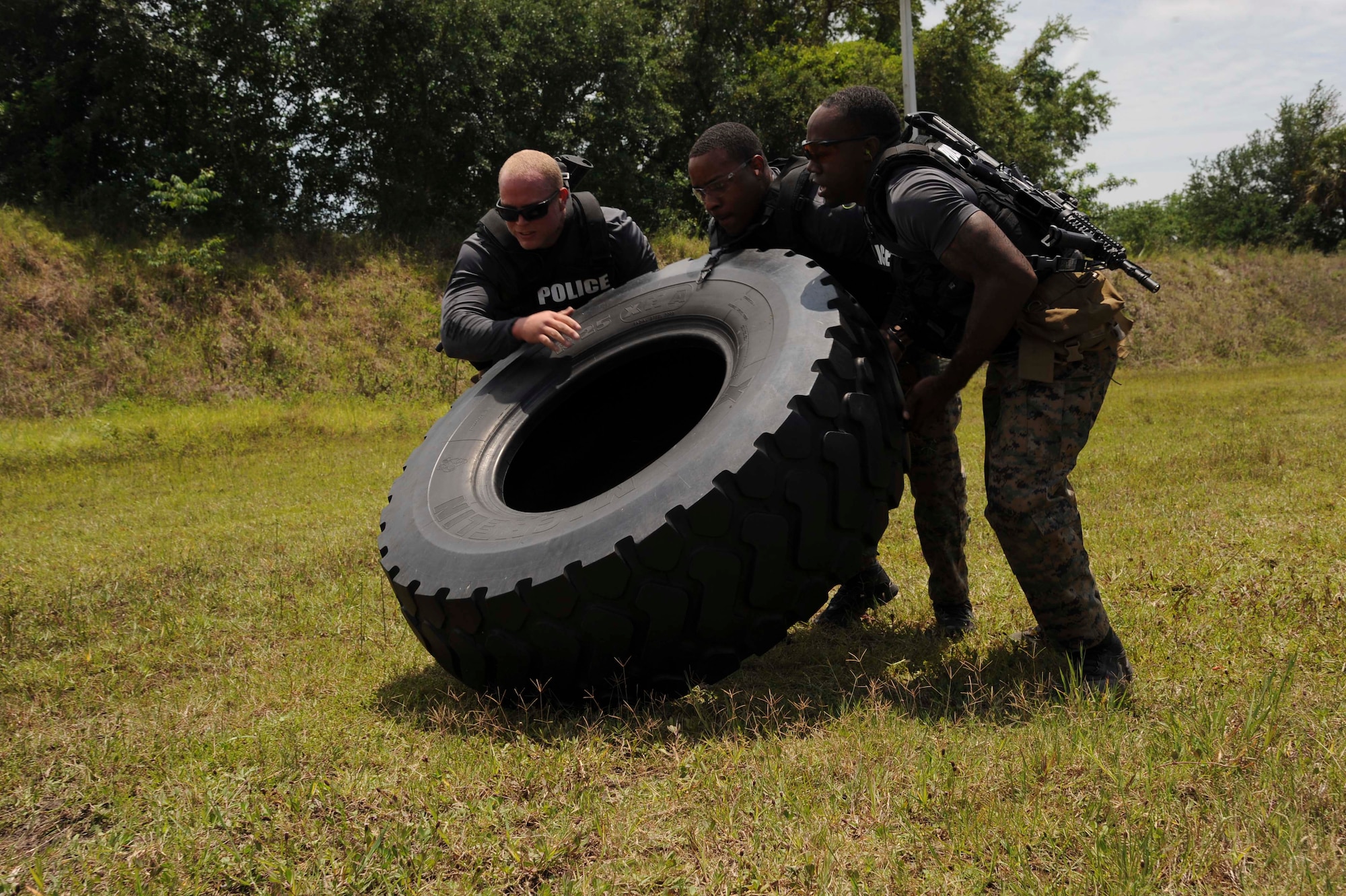 Officers from the Lakeland special weapons and tactics team flip a tire during the third annual tactical competition, May 13, 2016 at MacDill Air Force Base, Fla. The objective of the course was to test the officers’ physical and mental capabilities. (U.S. Air Force photo by Airman Adam R. Shanks)