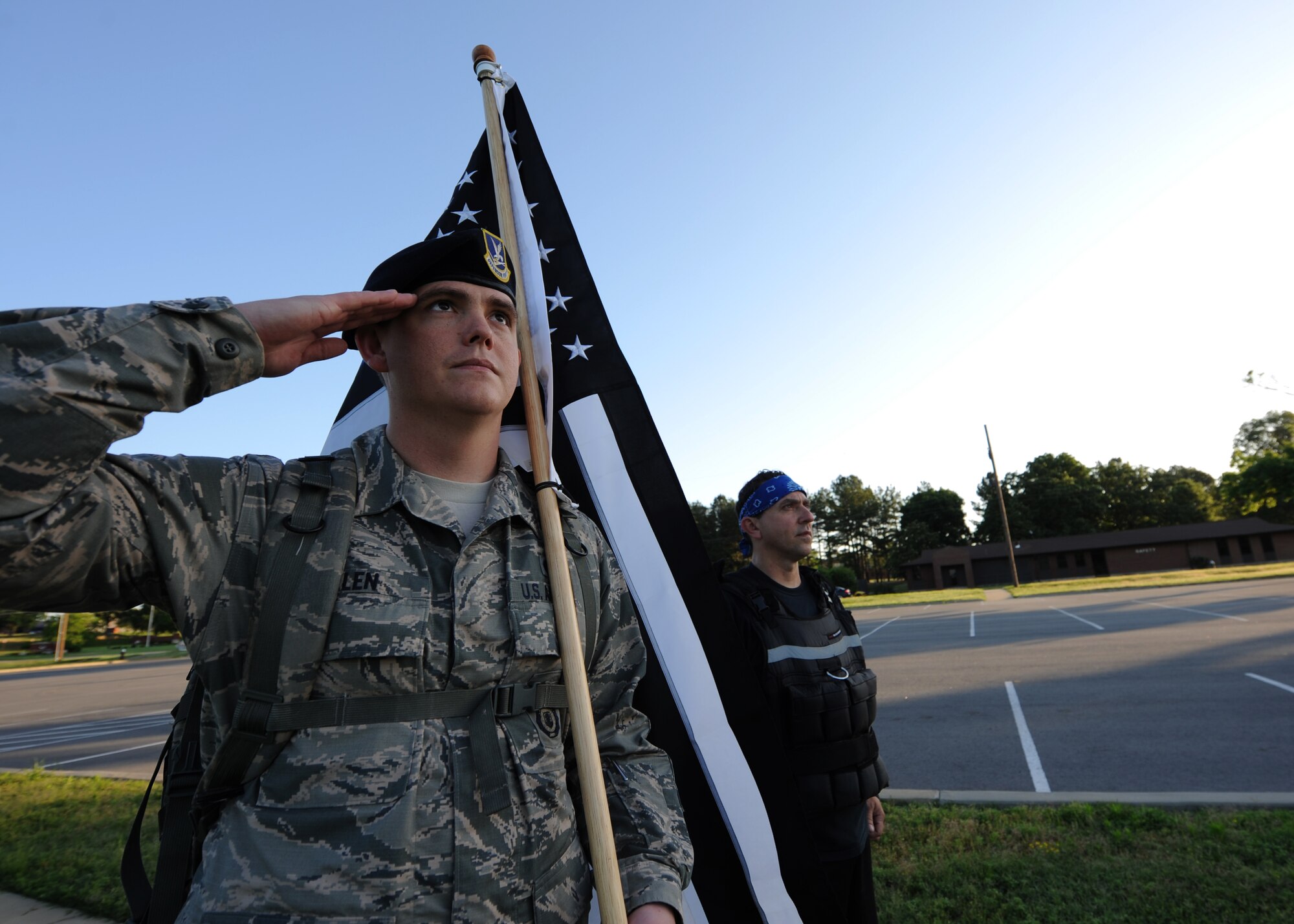 U.S. Air Force Senior Airman Christopher Allen, 19th Security Forces Squadron defender, and Shane Freestone, 19th Force Support Squadron federal policeman, salutes during Reveille while participating in the 24-hour ruck march for Police Week May 13, 2016, at Little Rock Air Force Base, Ark. A two-man team carried an additional 30 lbs each around Heritage Park. (U.S Air Force photo by Senior Airman Mercedes Taylor) 