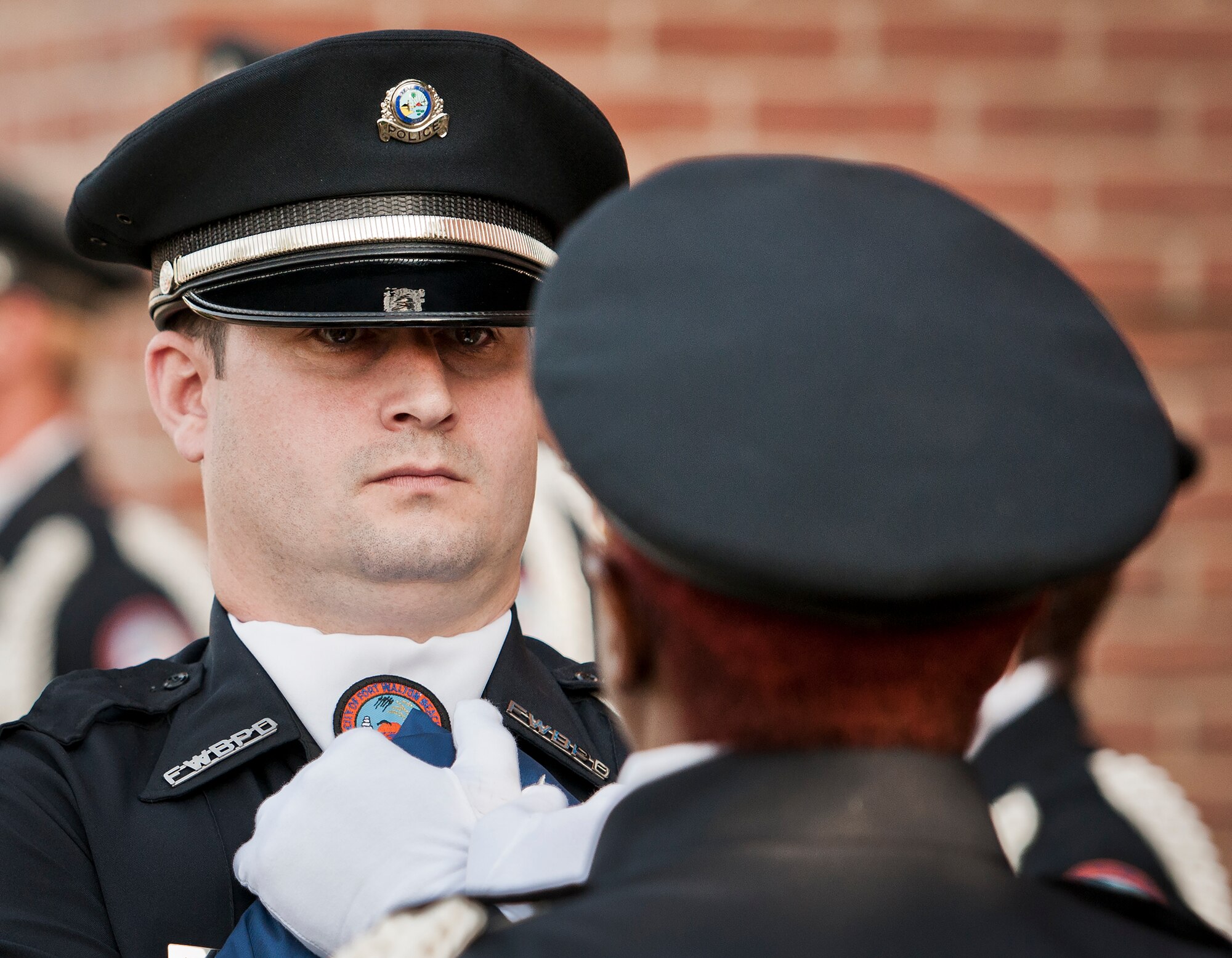 A police honor guard member carries the folded flag to the detail in charge of raising it to half-mast during the Peace Officers’ Memorial Ceremony May 16 in Fort Walton Beach, Fla.  The ceremony was to honor fallen police officers from the previous year by reading their names aloud.  Security forces Airmen from Eglin and Hurlburt Field attended and participated in the event.  The ceremony is one of many events taking place during National Police Week.  (U.S. Air Force photo/Samuel King Jr.)