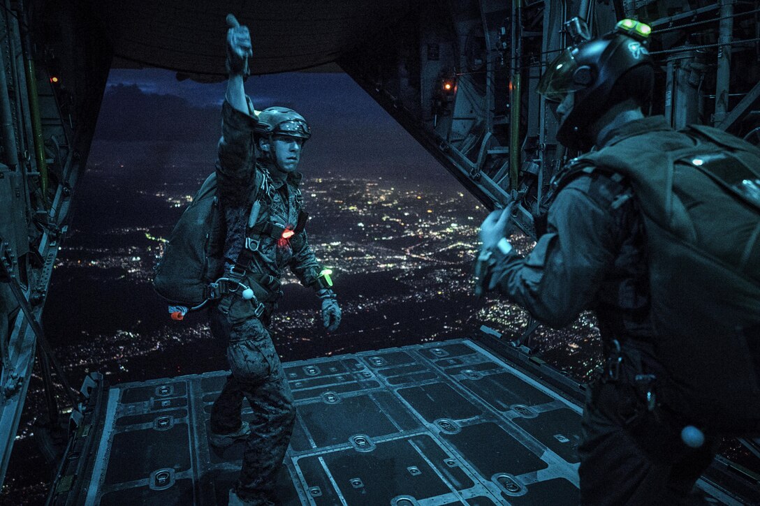 A Marine uses hand signals to communicate with fellow Marine jumpers in a C-130 Hercules over Yokota Air Base, Japan, May 11, 2016. The Marines, assigned to the 3rd Marine Division's 3rd Reconnaissance Battalion, 3rd Marine Expeditionary Force, conducted the night jump as part of yearly training. Air Force photo by Senior Airman Delano Scott