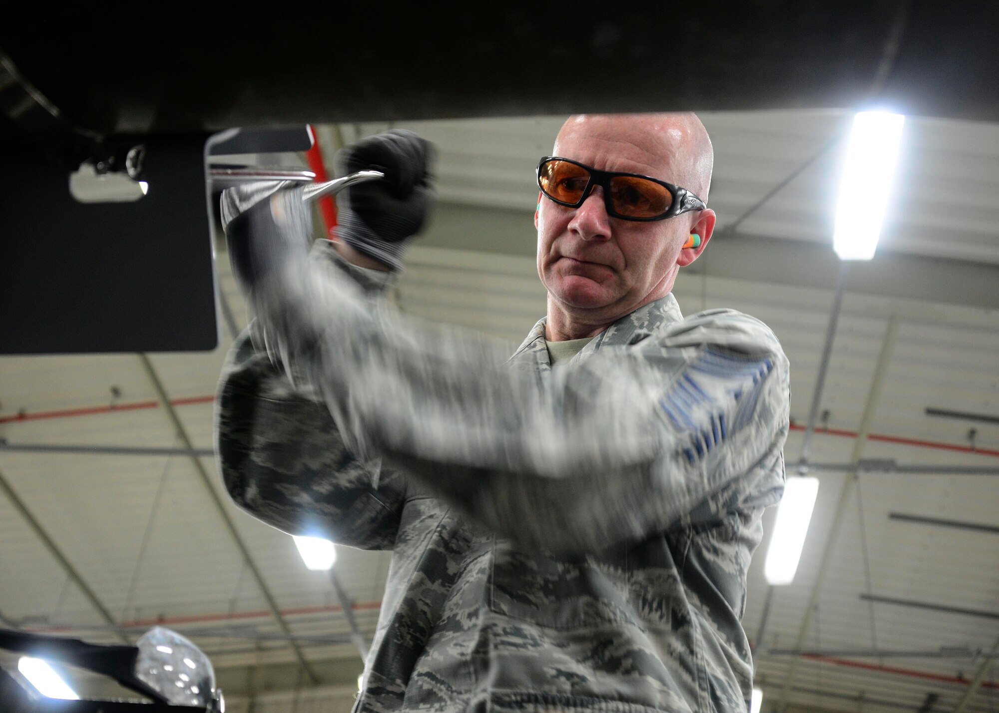 Chief Master Sgt. Thomas Good, 379th Air Expeditionary Wing command chief, uses a speed handle to tighten the aero-surface strake assembly on a guided bomb unit May 10, 2016, at Al Udeid Air Base, Qatar. Col. Samuel White, 379th AEW vice commander, and Good paid the 379th Expeditionary Maintenance Squadron Munitions Flight a visit to speak with Airmen directly and learn first-hand how the Airmen directly support precision air strikes throughout the region. (U.S. Air Force photo/Senior Airman Janelle Patiño/Released)