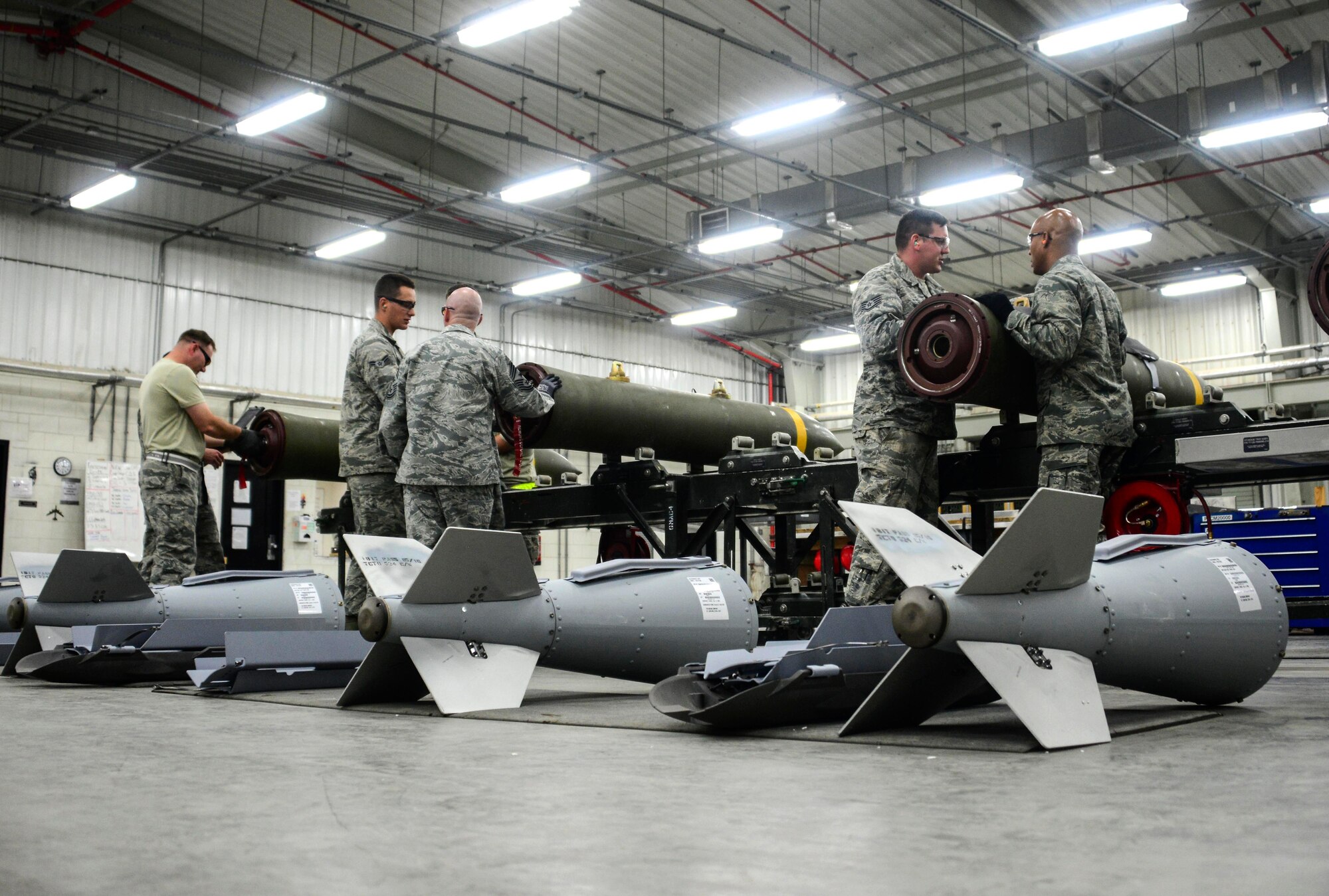 Members of the 379th Expeditionary Maintenance Squadron Munitions Flight teach Col. Samuel White, 379th Air Expeditionary Wing vice commander, and Chief Master Sgt. Thomas Good, 379th AEW command chief, how to build a bomb May 10, 2016, at Al Udeid Air Base, Qatar. White and Good visited the flight to not only learn how to build a bomb, but to also meet and speak directly with the deployed Airmen. (U.S. Air Force photo/Senior Airman Janelle Patiño/Released)