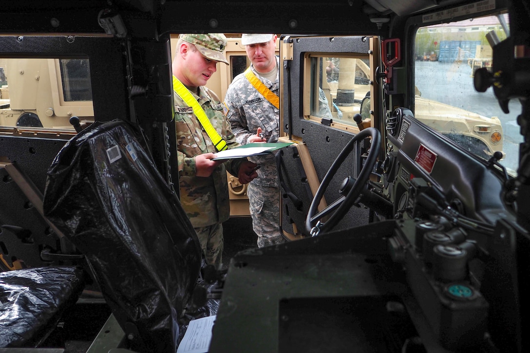 Army Spc. Cameron Henn, left, and Army Staff Sgt. Timothy Johnson review a technical manual before performing maintenance checks and services on vehicles at Joint Base Elmendorf-Richardson, Alaska, May 9, 2016. Henn and Johnson are assigned to the 17th Combat Sustainment Support Battalion. Air Force photo by Justin Connaher