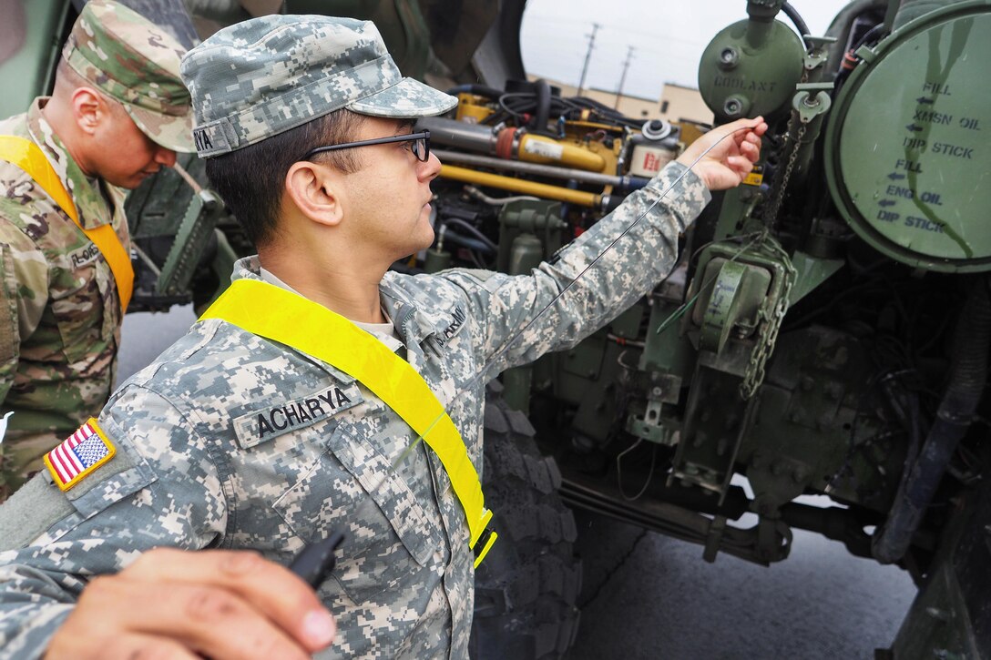 Army Spc. Sanjeev Acharya, foreground, checks oil levels while performing maintenance on vehicles at Joint Base Elmendorf-Richardson, Alaska, May 9, 2016. Acharya is assigned to the 17th Combat Sustainment Support Battalion. Air Force photo by Justin Connaher