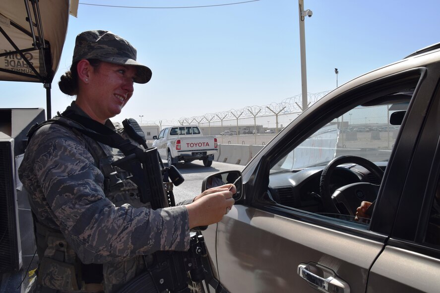Senior Airman Kalysta Nyquist-Asmussen checks an identification card as she reminds a passenger to fasten their seatbelt at an Al Udeid Air Base security gate May 14, 2016. The security forces Airmen are responsible for inspecting vehicles and passengers for suspicious activity prior to entering key areas of the base. (U.S. Air Force photo by Technical Sgt. Carlos J. Treviño)