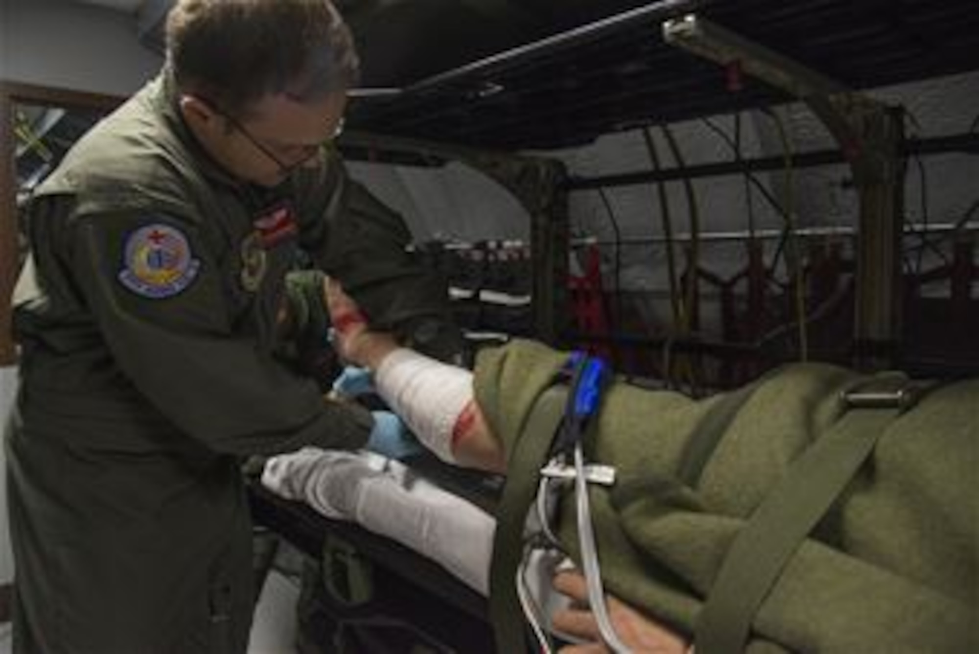 Staff Sgt. Dasha Ermanova, 375th Aeromedical Evacuation Squadron aeromedical evacuation technician, supports the leg of a simulated patient while Staff Sgt. Ryan Edwards, 375th AES aeromedical evacuation technician performs a dressing assessment on an injury on a new training simulator at Scott Air Force Base, Illinois on May 5, 2015. Aeromedical evacuation technicians are required to participate in the simulator two times every six months. (U.S. Air Force Photo by Airman Daniel Garcia)