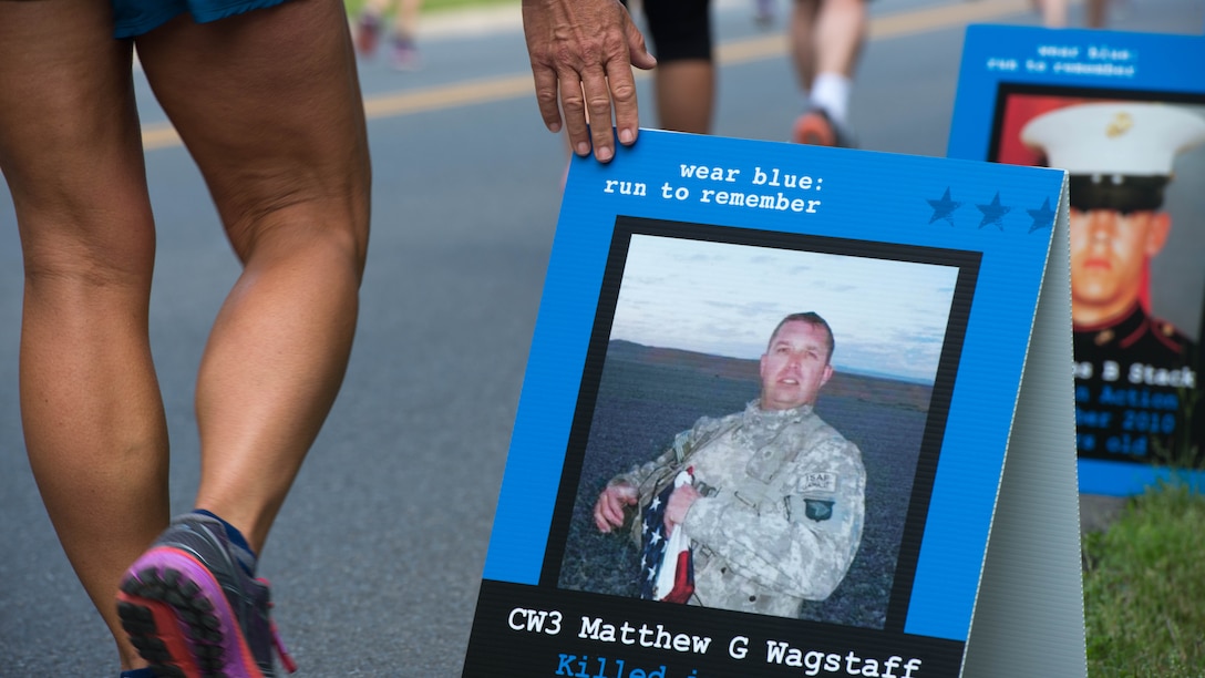 A participant walks through the Blue Mile at the Marine Corps Historic Half Marathon in Fredericksburg, Virginia, May 15, 2016. The participant paid her respects to the fallen U.S. military members by gently touching all of the dozens of signs on display. 