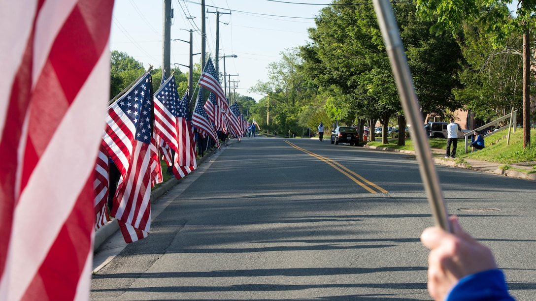 Dozens of volunteers hold American flags at the Blue Mile at the Marine Corps Historic Half Marathon in Fredericksburg, Virginia, May 15, 2016. The Blue Mile was an area of the course that was dedicated to U.S. service members who made the ultimate sacrifice for their country. 