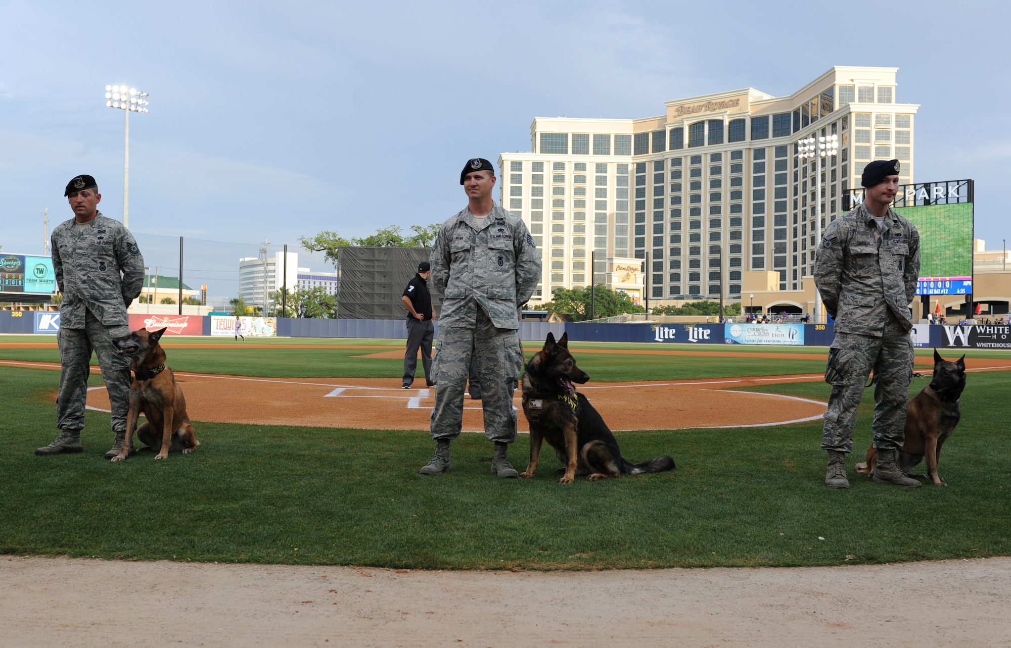 Tech. Sgt. James Martin, Staff Sgt. Javonnia Peak and Senior Airman Timothy Dawson, 81st Security Forces Squadron military working dog handlers, stand at ease with their military working dogs at MGM Park during a Biloxi Shuckers Minor League Baseball team pre-game ceremony May 9, 2016. The “Bark in the Park” themed baseball game invited fans to sit in the outfield seating area with their dogs. (U.S. Air Force photo by Kemberly Groue)