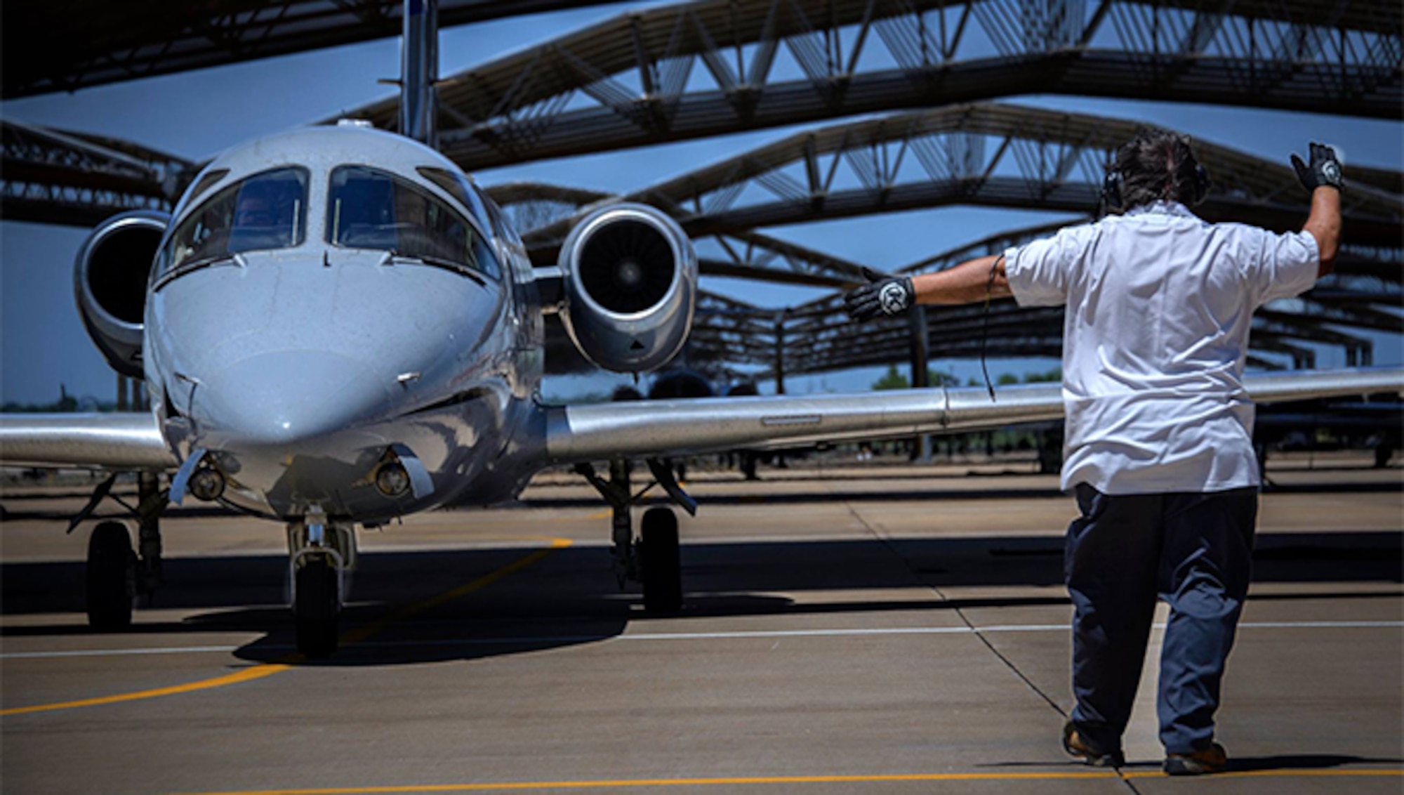 An L-3 Communications plane marshal ushers a T-1A Jayhawk crew toward the runway at Vance Air Force Base, Oklahoma. The 3rd Flying Training Squadron T-1 instructor pilots prepare students for a future in flying a variety of heavy aircraft like the C-17 Globemaster III cargo aircraft and the KC-135 Stratotanker aerial refueler. More than 300 student pilots earn silver wings annually at Vance AFB thanks to the dedication of active duty and Reserve instructors and civilian partners. (U.S. Air Force photo/ David Poe)