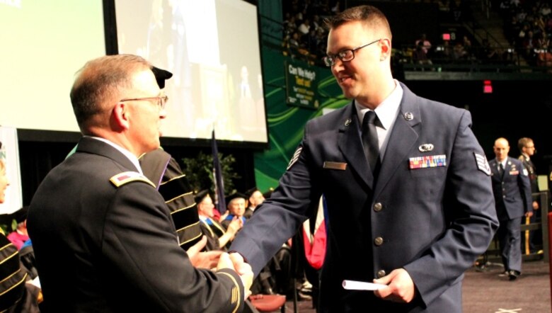 Staff Sgt. Matt Little crosses the stage at a commencement ceremony held at George Mason University on May 11, 2016, as he graduates from the Enlisted to Medical Degree Preparatory Program. The Enlisted to Medical Degree Preparatory Program is a partnership between the Armed Services and Uniformed Services University. Designed for enlisted service members, the two-year program enables members to remain on active duty status while enrolled as full-time students in preparation for application to medical school. (U.S. Air Force photo by Prerana Korpe, AFMS Public Affairs)