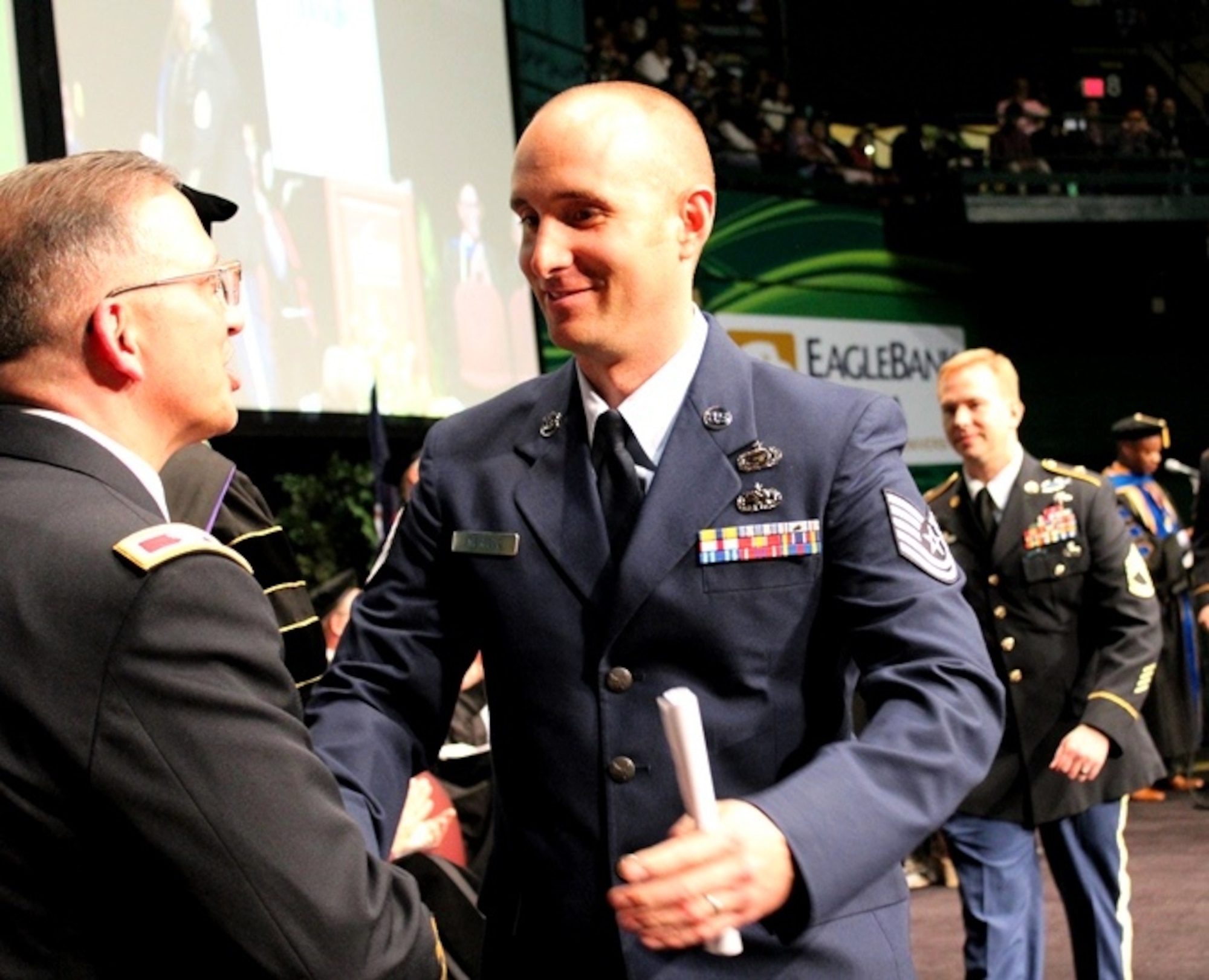 Tech. Sgt. Joe Merfeld crosses the stage at a commencement ceremony held at George Mason University on May 11, 2016, as he graduates from the Enlisted to Medical Degree Preparatory Program. The Enlisted to Medical Degree Preparatory Program is a partnership between the Armed Services and Uniformed Services University. Designed for enlisted service members, the two-year program enables members to remain on active duty status while enrolled as full-time students in preparation for application to medical school. (U.S. Air Force photo by Prerana Korpe, AFMS Public Affairs)
