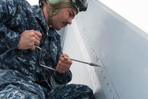 U.S. Navy Aviation Machinist Mate 2nd Class Joseph Neely, from VAQ-137, Naval Air Station Whidbey Island, Washington, tightens screws after finding one loose while inspecting panels on an EA-18G Growler aircraft prior to a sortie May 9, 2016 during RED-FLAG-Alaska (RF-A) 16-1 at Eielson Air Force Base, Alaska. The aircraft logged more than 500 tactical flying hours during RF-A 16-1, which requires maintainers to work around the clock. (U.S. Air Force photo by Staff Sgt. Shawn Nickel/Released)