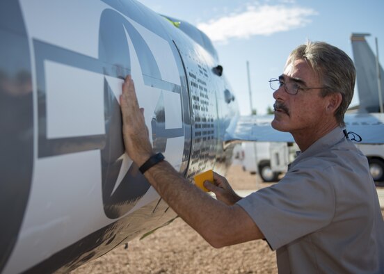 Mike, an M1 Support Systems aircraft corrosion specialist at Holloman Air Force Base N.M., smooths wrinkles out of a decal on an F-84F Thunderstreak after sanding and re-painting it at Heritage Park here May 16. The F-84F Thunderstreak was used by Strategic Air Command, Tactical Air Command, the Air National Guard and NATO Air Forces during the Korean War. (Last names are being withheld do to operational requirements) (U.S. Air Force photo by Airman 1st Class Randahl J. Jenson)   