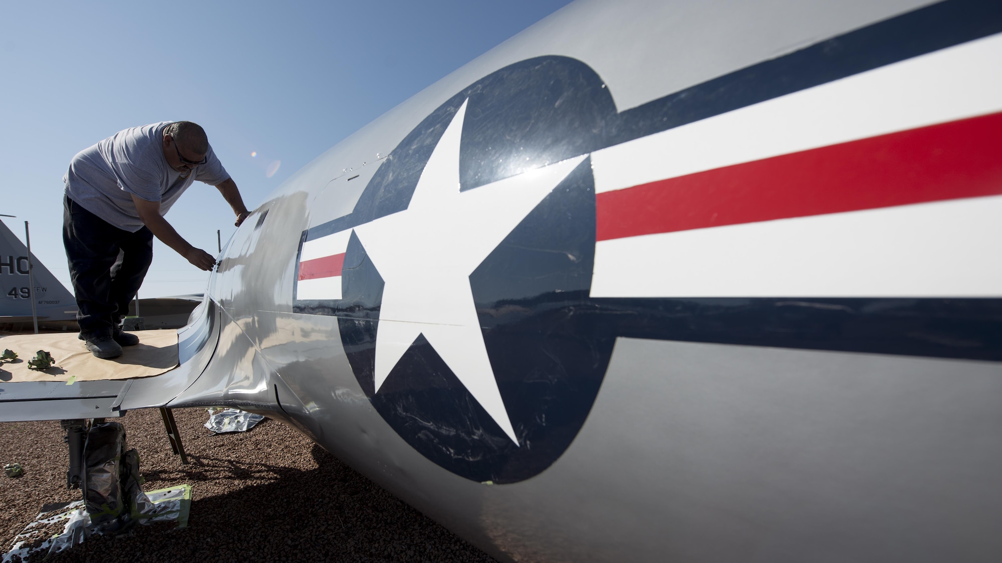 Carlos, an M1 Support Systems aircraft corrosion specialist at Holloman Air Force Base N.M., removes tape used for painting straight lines on a P-80B Shooting Star at Heritage Park here May 16. The P-80B Shooting Star was the first U.S. Air Force jet to be used in combat. This particular jet, Serial Number 49-853, flew combat missions during the Korean War. (Last names are being withheld do to operational requirements) (U.S. Air Force photo by Airman 1st Class Randahl J. Jenson)
