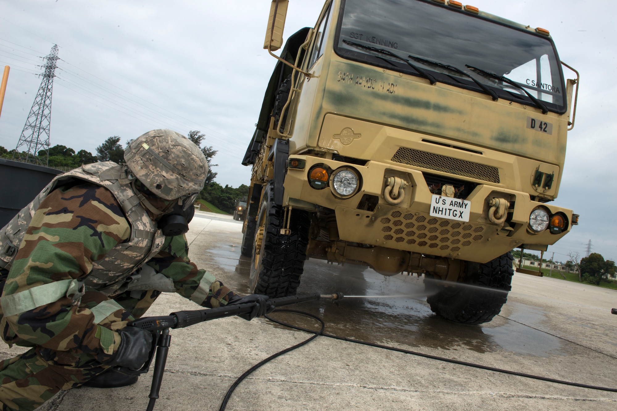 A U.S. Army Soldier from the 1-1 Air Defense Artillery Headquarters and Headquarters Battalion sprays down an Army vehicle while wearing mission-oriented protective posture gear during a joint decontamination exercise May 12, 2016, at Kadena Air Base, Japan. For the first time in recent history, the Army on Kadena teamed up with Air Force chemical, biological, radiological, and nuclear decontamination experts to practice the safe decontamination of military and vehicles to better prepare them for potential real-world threats in the future. (U.S. Air Force photo by Staff Sgt. Maeson L. Elleman)