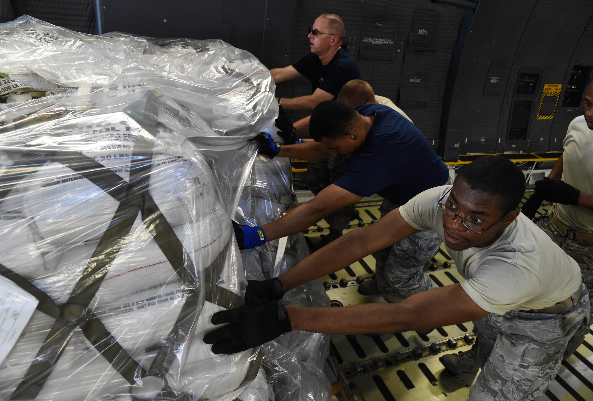 Members of the 612th Air Base Squadron move a pallet towards a K Loader while aboard a C-5M Super Galaxy from Dover Air Force Base, Del., at Soto Cano Air Base, Honduras, May 13, 2016. Through the Denton Program, the C-5 delivered approximately 85,000 pounds of rice and beans which is to be distributed to people in the Yoro Department of Honduras by a local non-governmental organization. (U.S. Air Force photo by Staff Sgt. Siuta B. Ika)
