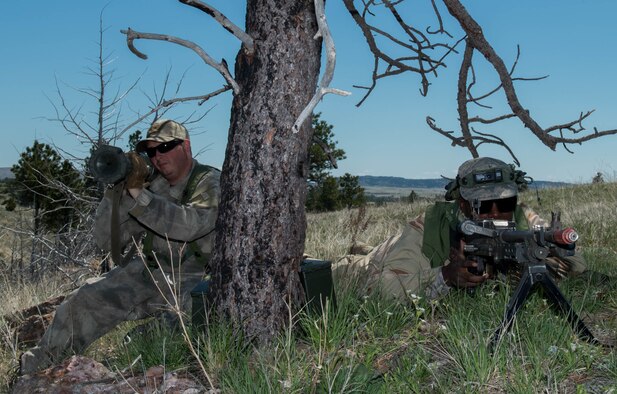 Staff Sgt. Brian Gill, left, 821st Contingency Response Squadron defender and Senior Airman Dennis Marshall, 921st Contingency Response Squadron defender, take cover under a tree and wait for a missile convoy attack scenario during exercise Road Warrior at Camp Guernsey, Wyo., May 4, 2016. The 621st CRW Airmen played the opposing force for the Global Strike Command exercise, which evaluates tactics, techniques, and procedures used to secure nuclear–capable weapons and critical intercontinental ballistic missile components during convoy operations. (U.S. Air Force photo by Staff Sgt. Robert Hicks/Released)