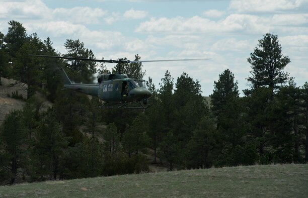 A UH-1 Huey helicopter circles overhead to patrol the area and look for the opposing forces during exercise Road Warrior at Camp Guernsey, Wyo., May 3, 2016. The 621st CRW Airmen played the opposing force for the Global Strike Command exercise, which evaluates tactics, techniques, and procedures used to secure nuclear–capable weapons and critical intercontinental ballistic missile components during convoy operations. (U.S. Air Force photo by Staff Sgt. Robert Hicks/Released)