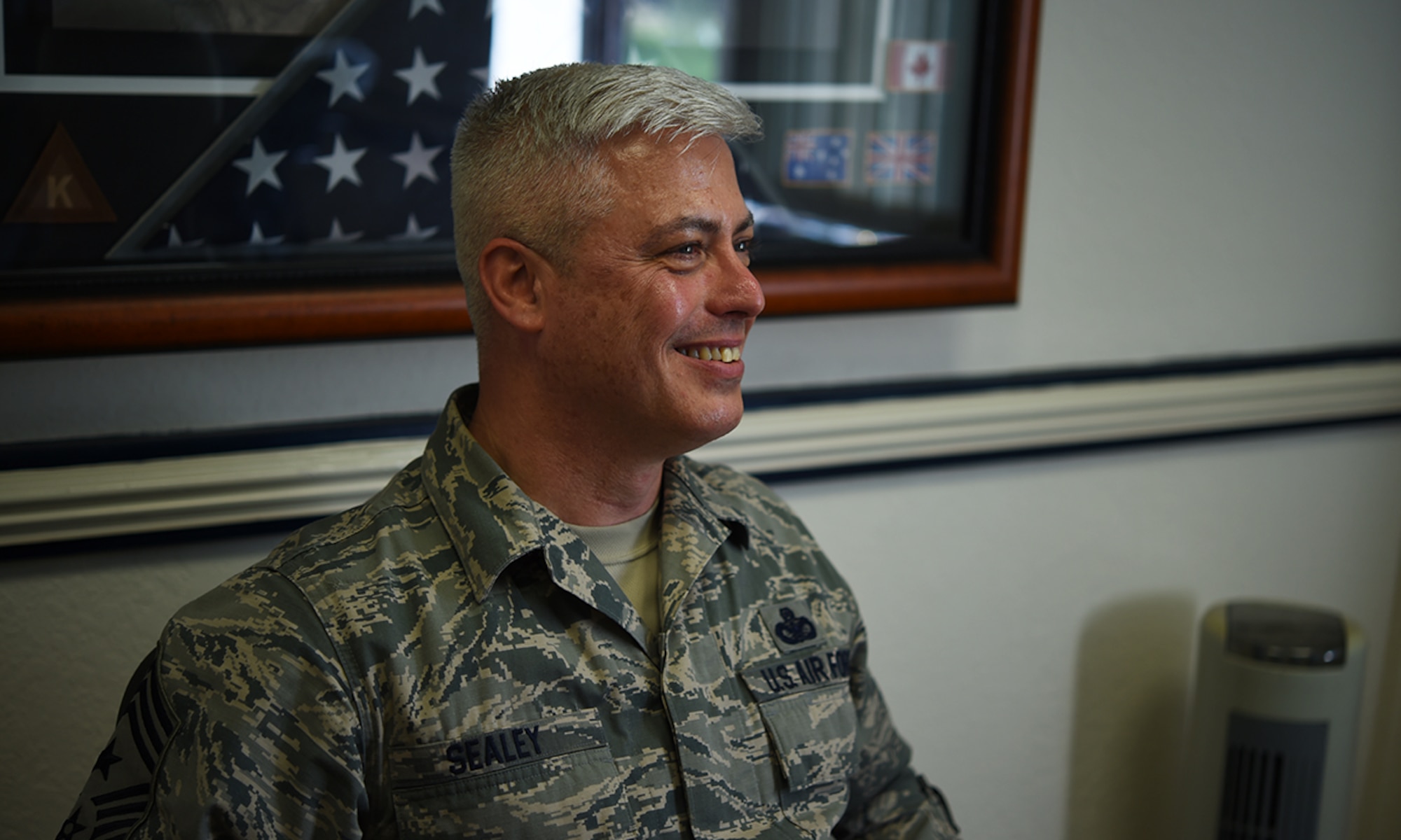 Chief Master Sgt. Robert Sealey, 501st Combat Support Wing command chief, smiles broadly, inside his office on RAF Alconbury, United Kingdom, April 28, 2016, while recalling the "best day" through his 30 year career in the U.S. Air Force. It wasn't making rank, the accolades or awards, Sealey said - it was watching his son graduate from Air Force basic military training. (U.S. Air Force photo by Tech. Sgt. Jarad A. Denton/Released)