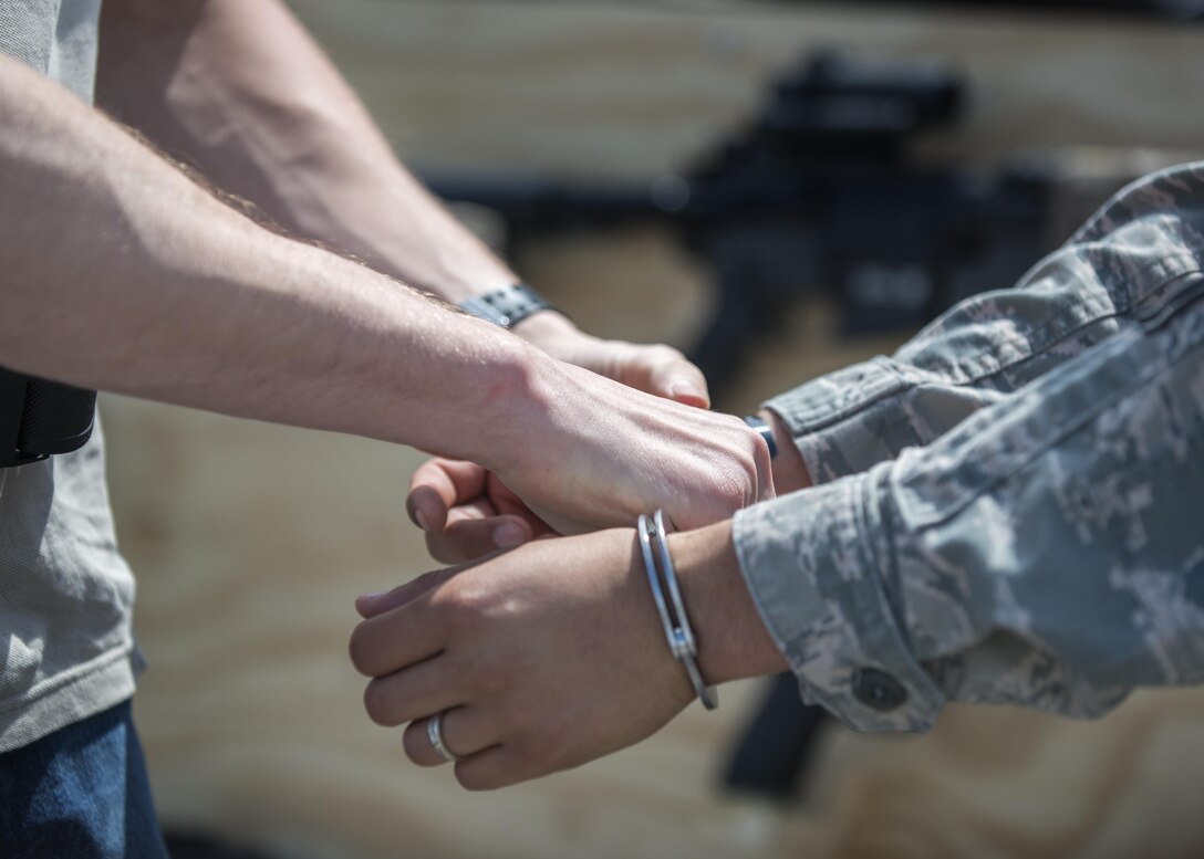 A 31st Security Forces Squadron member simulates apprehending a suspect during a Military Working Dog demonstration for National Police Week May 16, 2016, at Aviano Air Base, Italy. The demonstration was performed to showcase capabilities of MWDs and their handlers. (U.S. Air Force photo by Airman 1st Class Cory W. Bush/Released)